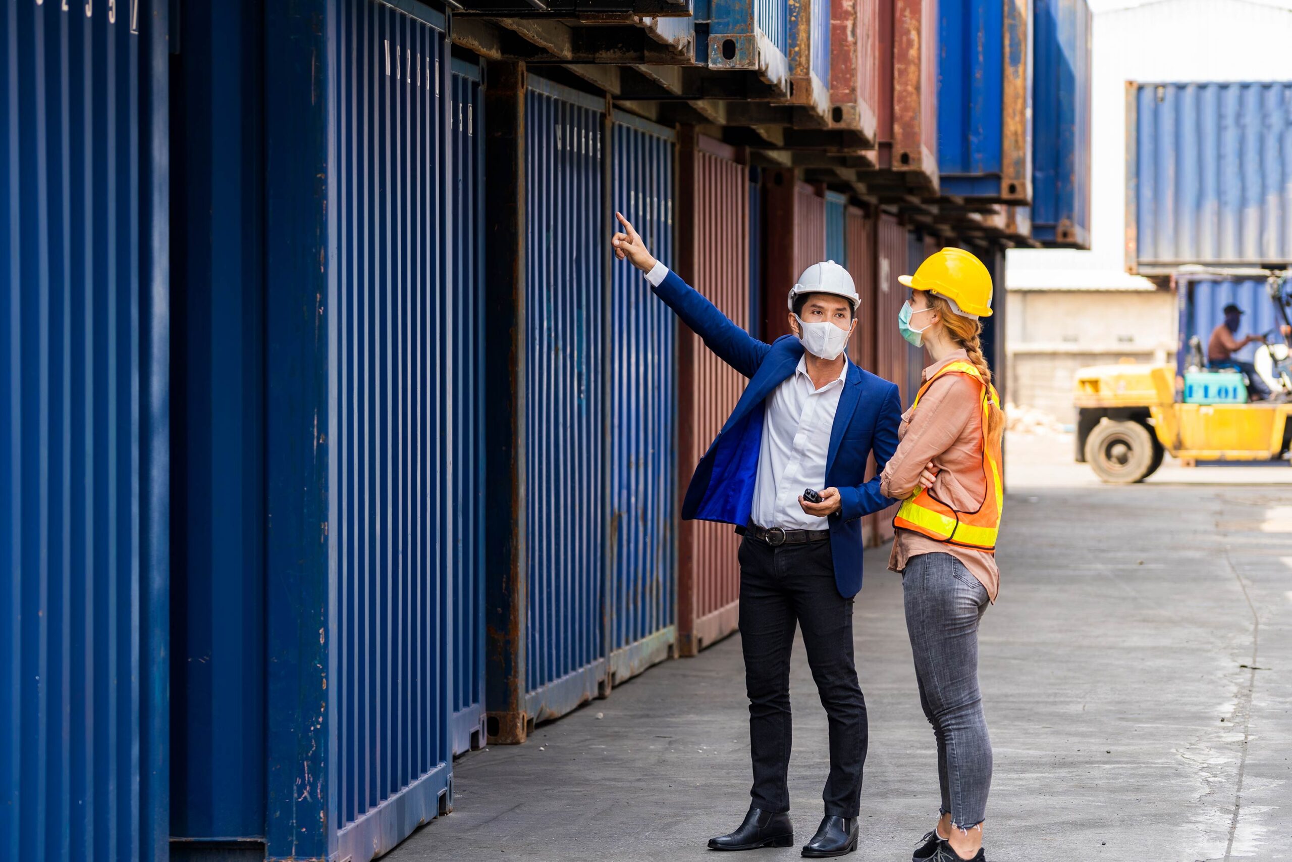 two-engineer-worker-hold-laptop-document-checking-quality-containers-box-from-cargo-ship-export-import-blue-container-background